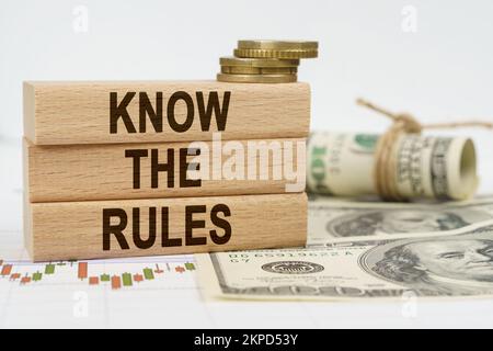 Geschäfts- und Finanzkonzept. Auf dem Tisch liegen Dollars, Finanzkarten und Holzteller, auf denen es steht - KENNEN SIE DIE REGELN Stockfoto