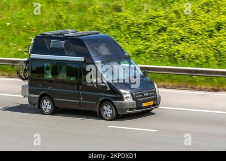 Ford Transit High-Top, ausländisches schwarzes Wohnmobil, mit Solarpaneelen, auf der Autobahn M6, Großbritannien Stockfoto