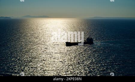 Frachtschiff auf See. Transitschiff. Segelboote. Fischerboot. Angeln. Besichtigungsboot. Boot, Schiff schwimmt in blauem Wasser. Sonnenbrand und Schiffsreflexion Stockfoto