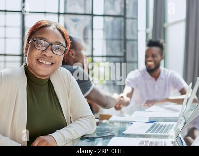 Schöne junge grinsende professionelle schwarze Frau im Büro Stockfoto