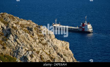 Frachtschiff auf See. Transitschiff. Segelboote. Fischerboot. Angeln. Besichtigungsboot. Boot, Schiff schwimmt in blauem Wasser. Sonnenbrand und Schiffsreflexion Stockfoto