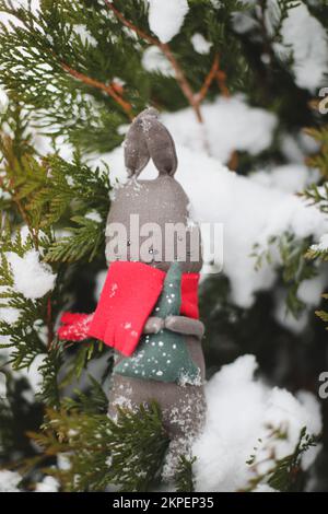 Frohe Weihnachten und Frohes neues Jahr. Spielzeugkaninchen, das an einem Weihnachtsbaumzweig hängt, Symbol von 2023 Stockfoto
