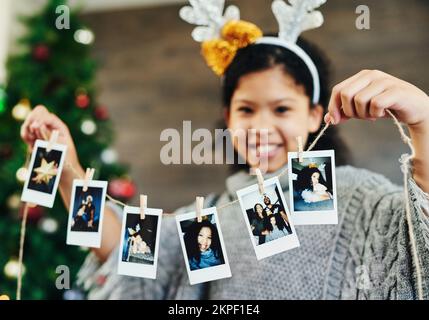 Mädchenporträt, polaroid und weihnachtsfeier, fröhliches Lächeln und Erinnerungen, Foto und Dekoration zu Hause. Kind, Bild und Schnur für Weihnachten Stockfoto