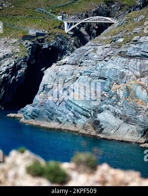 Fußgängerbrücke aus Stahlbeton über eine dramatische Meeresschlucht, die Cloghane Island mit dem Festland verbindet, Mizen Head Peninsula, County Cork, Irland Stockfoto