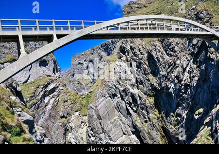 Fußgängerbrücke aus Stahlbeton über eine dramatische Meeresschlucht, die Cloghane Island mit dem Festland verbindet, Mizen Head Peninsula, County Cork, Irland Stockfoto