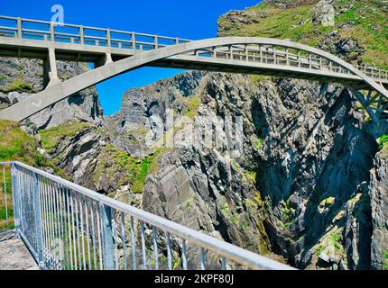 Fußgängerbrücke aus Stahlbeton über eine dramatische Meeresschlucht, die Cloghane Island mit dem Festland verbindet, Mizen Head Peninsula, County Cork, Irland Stockfoto