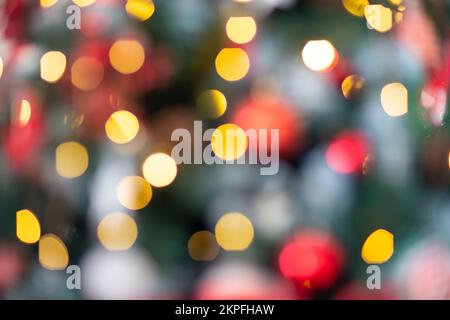 Nahaufnahme eines festlich dekorierten Weihnachtsbaums im Freien mit Bällen auf einem verschwommenen funkelnden Feenhintergrund. Unschärfe-Girlande-Lichter, Bokeh-Effekt. Stockfoto