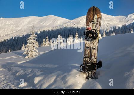 Marmaros, Karpaten, UKRAINE - Februar 11 2021: Snowboard mit einem Gebirgsmuster im Hintergrund einer Bergkette und einem blauen Himmel Stockfoto