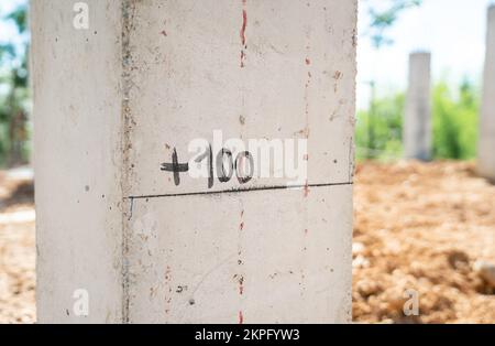 Nahaufnahme der Stahlbetonsäulenstruktur mit schriftlichen Angaben zur Höhe bei 100 cm. Vom Boden auf einer Baustelle im Vorort. Stockfoto