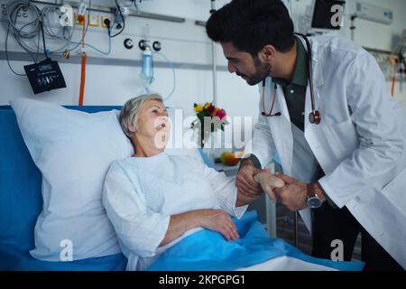 Junger Arzt, der den Blutdruck beim Seniorpatienten überprüft. Stockfoto