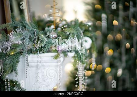 Nahaufnahme eines festlich dekorierten Weihnachtsbaums im Freien mit Bällen auf einem verschwommenen funkelnden Feenhintergrund. Unschärfe-Girlande-Lichter, Bokeh-Effekt. Stockfoto