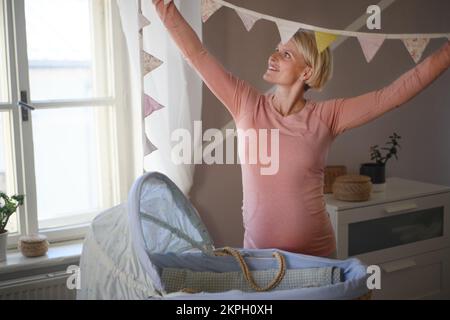 Schwangere Frau bereitet ein Zimmer für ihr Baby vor. Stockfoto