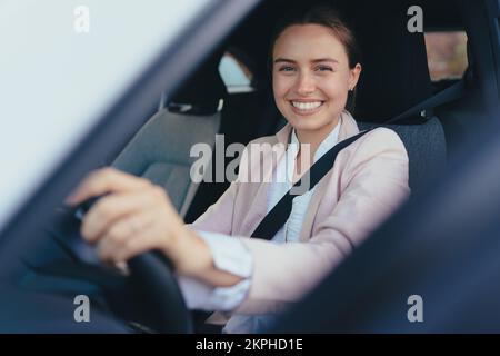 Aufgeregte junge Frau, die in ihrem Auto sitzt und sich auf das Fahren vorbereitet. Stockfoto