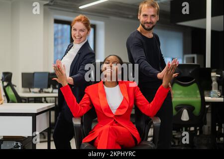 Weiß, rothaarige Frau, bärtiger weißer Mann, High, fünf afroamerikanische junge Frau im Büro. Stockfoto