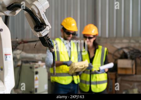 Robotikingenieur, der an der Wartung des modernen Roboterarms im Fabriklager arbeitet Stockfoto