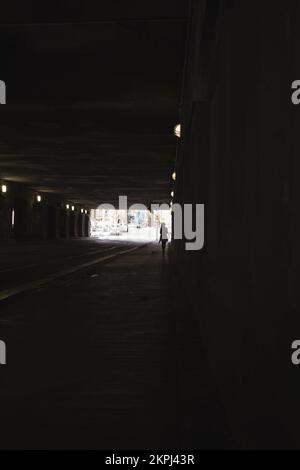 Eine Frau, die unter einer dunklen Brücke läuft Stockfoto