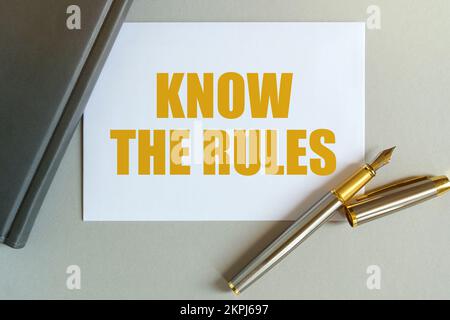 Geschäfts- und Finanzkonzept. Auf dem Tisch befinden sich ein Notizbuch, ein Stift und eine Visitenkarte mit der Aufschrift – KENNEN SIE DIE REGELN Stockfoto