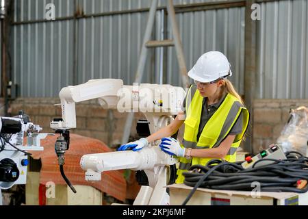 Robotikingenieur, der an der Wartung des modernen Roboterarms im Fabriklager arbeitet Stockfoto