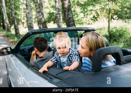 Mama, Papa und kleiner Sohn in einem Cabriolet. Sommer Familienausflug in die Natur Stockfoto