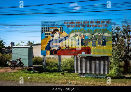 Eine vietnamesische Kommunistische Partei malte Propagandafilter, auf denen ethnische Minderheiten dargestellt werden, die Gfongs spielen und einen Traktor fahren. Die Plakatwand drängt auf Pups Stockfoto