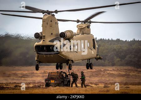 Soldaten, die ein militärisches Geländefahrzeug an einen Boeing CH-47F Chinook Hubschrauber angreifen. Ginkelse Heide, Niederlande - 17. September 2022 Stockfoto