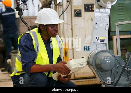 Robotikingenieur, der an der Wartung des modernen Roboterarms im Fabriklager arbeitet Stockfoto