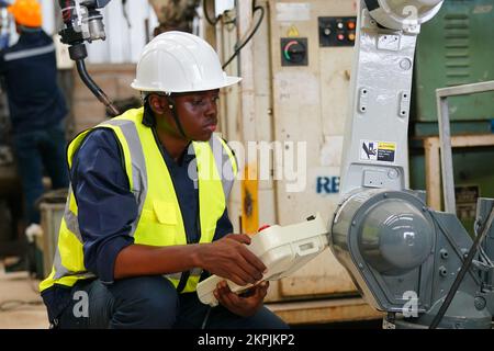 Robotikingenieur, der an der Wartung des modernen Roboterarms im Fabriklager arbeitet Stockfoto