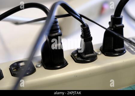 Viele Netzstecker sind eingesteckt, und die Kabel sind durcheinander und unorganisiert Stockfoto