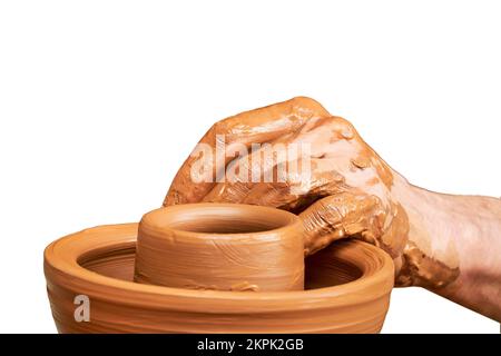 Ein Mann in alter byzantinischer Kleidung sitzt hinter einem alten Töpferrad und macht Gerichte aus Ton, isoliert auf weißem Hintergrund. Töpferei rein Stockfoto