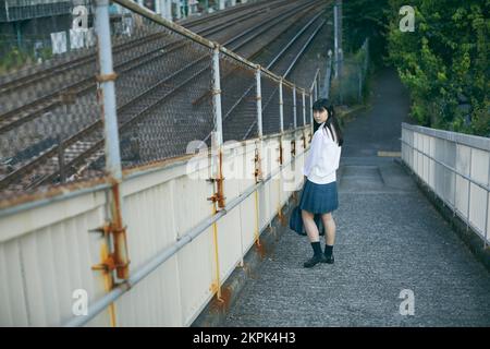 Japanisches Highschool-Mädchen auf einer Fußgängerbrücke Stockfoto