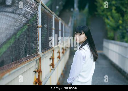 Japanisches Highschool-Mädchen auf einer Fußgängerbrücke Stockfoto