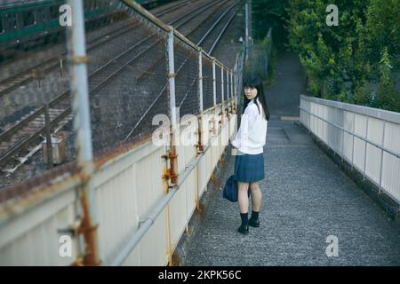 Japanisches Highschool-Mädchen auf einer Fußgängerbrücke Stockfoto