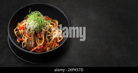 Pasta mit Fleisch, Pilzen und Gemüse, auf einem hölzernen Hintergrund, mit verschwommenem Hintergrund Stockfoto