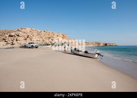 Zwei Fischer, die von ihrem Boot mit einem weißen Pickup an einem Strand von Ras Al Jinz, Sultanat von Oman, abfuhren Stockfoto