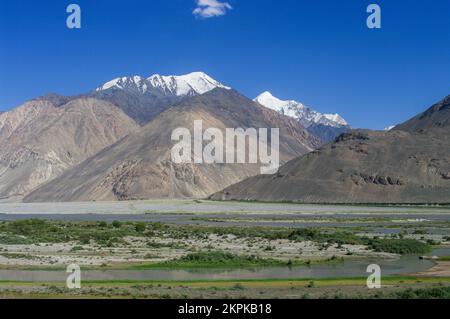 Landschaftsblick auf die schneebedeckten Berge von Hindu Kush auf der afghanischen Seite des Flusstals Panj im Wakhan-Korridor, Gorno-Badakshan, Tadschikistan Pamir Stockfoto