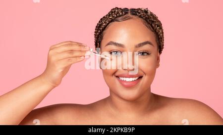 Hautpflege- und Schönheitskonzept. Glückliche schwarze Körper positive Frau hält Dropper mit nährendem Gesichtsserum, Panorama Stockfoto