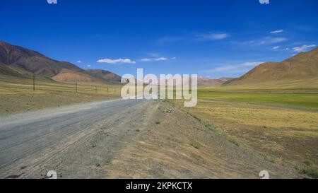 Malerische Berglandschaft auf einem langen, geraden Straßenabschnitt auf dem hoch gelegenen Pamir Highway nahe Murghab, Gorno-Badakshan, Tadschikistan Stockfoto