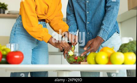 Abgeschnittenes Bild von afroamerikanischen Ehepartnern, die gesundes vegetarisches Essen in der Küche kochen, Panorama, Nahaufnahme Stockfoto