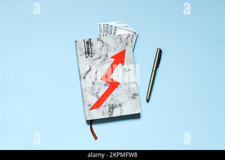 Steigende Lebenshaltungskosten, Inflation, Finanz- und Wirtschaftskrise. Notizbuch mit Geldscheinen und rotem Pfeil auf blauem Hintergrund. Stockfoto