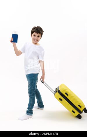 Ein durchgehender porträtierter Teenager in blauen Jeans und weißem T-Shirt, mit Flugticket und Koffer in den Sommerferien Stockfoto