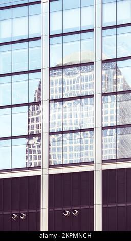 Das Gebäude spiegelt sich in den Fenstern eines modernen Wolkenkratzers wider, abstrakter urbaner Hintergrund, Farbtöne angewendet, New York City, USA. Stockfoto