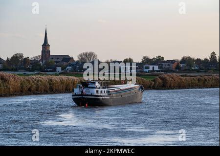 Berlare, Ostflämische Region, Belgien, 11 02 2022 - Sonnenuntergang über der Schelde mit einem vorbeifahrenden Schiff Stockfoto