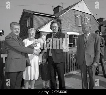 1980er, historisch, steht draußen für ein Werbefoto, mit Geschäftsführern von Bauunternehmen, einem Paar mit einer jungen Tochter, dem Mann, der den Schlüssel zu ihrem neuen Zuhause in England, Großbritannien, erhält. Stockfoto