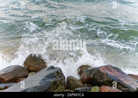 Große Felsen am Ufer. Die Wellen des Meeres stürzen auf die Felsen. Steiniger Küstenabschnitt. Stockfoto