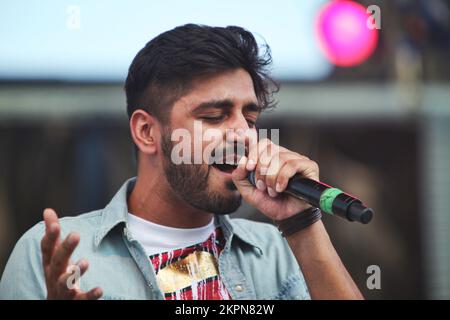 August 2013, Mississauga, Ontario, Kanada. --- Leadsänger Sups der britischen Band Swami belebt das Publikum, während Swami beim Mosaik 2013 South Asian Heritage Festival in Mississauga auftritt. Swami kombiniert Punjabi, Hindi und Englisch und kombiniert Bhangra, Rock und Rap zu einem einzigartigen Musikstil, der sich im gesamten Vereinigten Königreich ausgebreitet hat. Ihr Sound ist eine perfekte Hommage an die unabhängige Punjabi-Musik, die sich in Großbritannien in den letzten 30 Jahren entwickelt hat. --- (Foto von Creative Touch Imaging Ltd./NurPhoto) Stockfoto