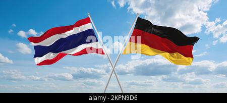 Zwei überkreuzte Flaggen Bundesrepublik Deutschland und Thailand winken im Wind am bewölkten Himmel. Beziehungskonzept, Dialog, Reisen zwischen zwei Zählungen Stockfoto