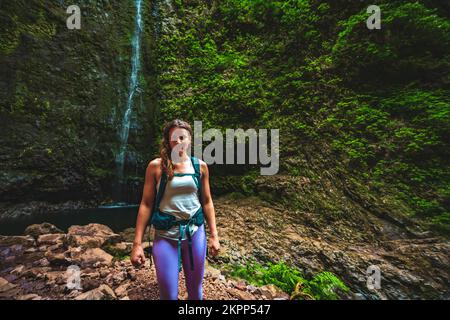 Beschreibung: Wunderschöne sportliche Frau mit Rucksackwanderungen am herrlichen Dschungelwasserfall. Levada von Caldeirão Verde, Insel Madeira, Portugal, Europa. Stockfoto