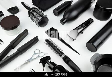 Stellen Sie Friseuraccessoires auf weißen Hintergrund. Zusammensetzung mit Schere, Spray, Shampoo, Bürste, Lockenstab, Kammaufsatz, Haarschneider, anderes Haar Stockfoto