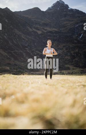 Eine ruhige Frau, die Yoga auf einer alpinen Wiese macht, mit ihren Händen in Gebetsstellung, Gastein, Österreich Stockfoto