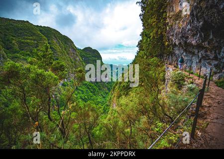 Beschreibung: Sportliche Frau mit Rucksackwanderungen auf einem abenteuerlichen Dschungelweg entlang des Kanals. Levada Caldeirão Verde, Insel Madeira, Portugal, EUR Stockfoto
